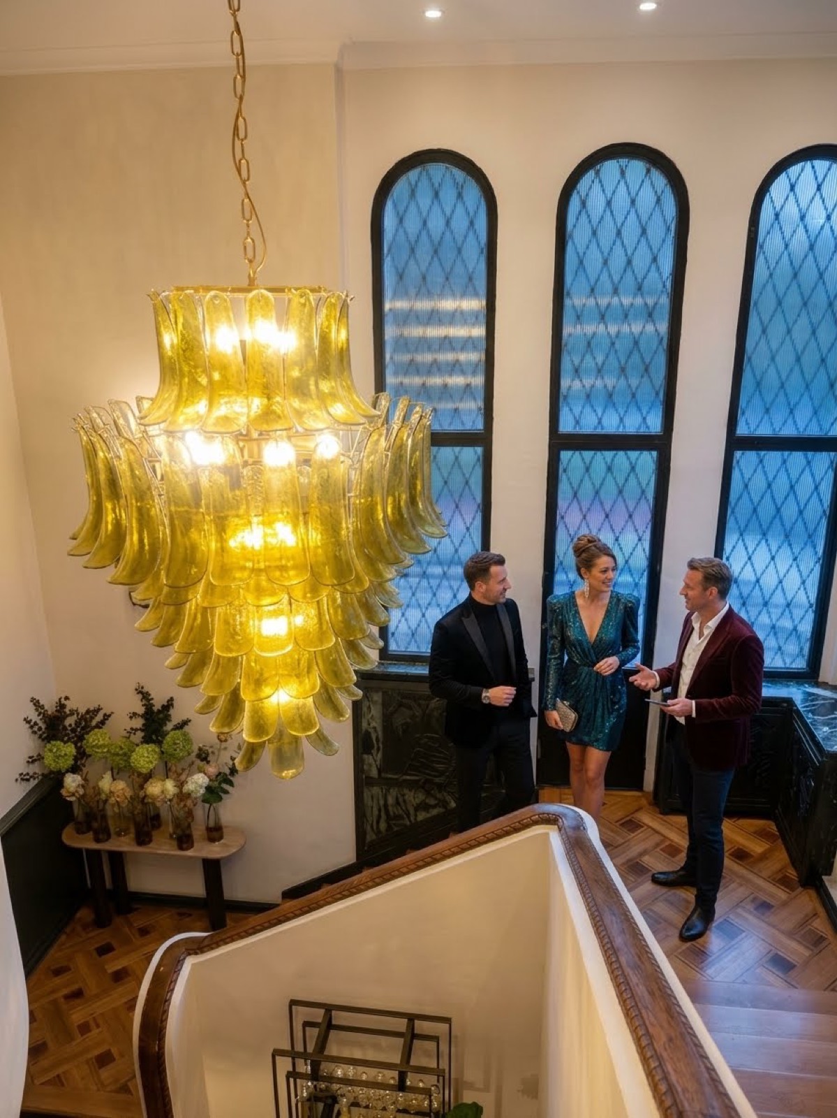 Guests in conversation beneath a gold chandelier at a MAGOCLUB gathering.