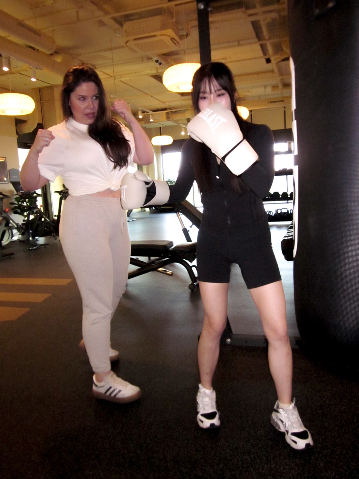 Maria Elena Cismarescu in guard beside a gloved client at the heavy bag.