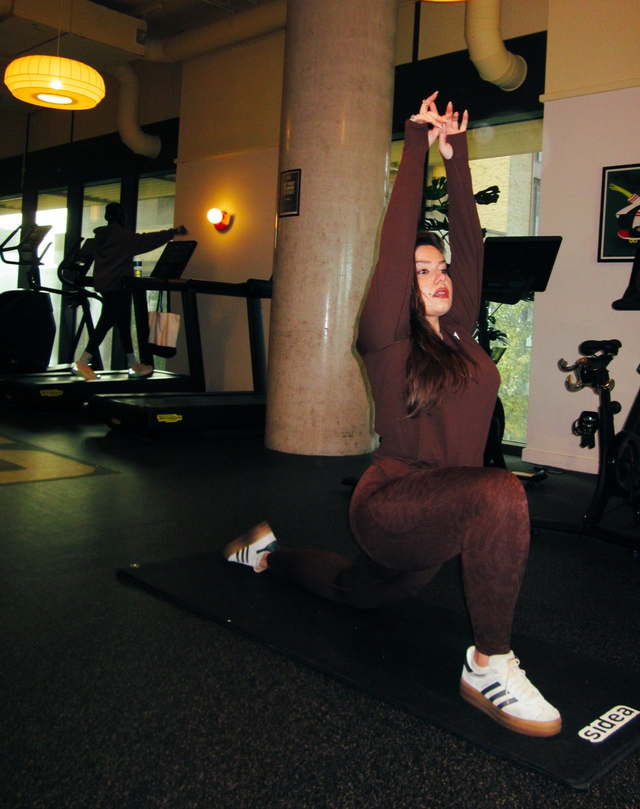 Maria Elena Cismarescu in a deep kneeling stretch on the studio floor.